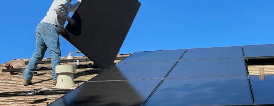 Worker on roof installing solar panels